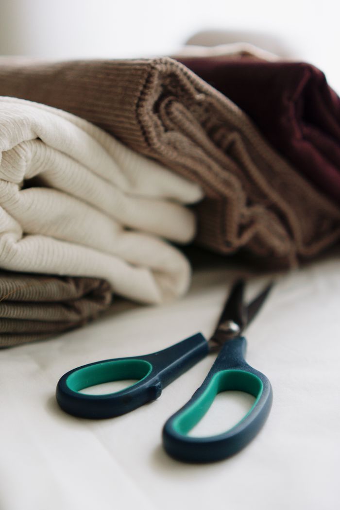 Close-up of folded fabric with teal-handled scissors, perfect for sewing projects.